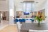 Modern open-concept kitchen and dining area with chic blue chairs, stainless steel range hood, and vibrant floral centerpiece.