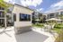 Modern apartment complex courtyard featuring vibrant green lawns, elegant seating areas, and a stylish outdoor TV, surrounded by lush palm trees for a resort-style experience.