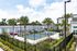 Modern apartment complex featuring vibrant tennis courts, lush palm trees, and elegantly landscaped surroundings.