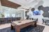 Chic entertainment room featuring a modern pool table, stylish bar seating, designer lighting, and a vibrant hexagonal wall design.