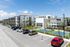 Modern apartment complex with spacious balconies, ample parking, and vibrant tennis courts set against a clear blue sky.