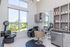 Chic salon interior featuring modern styling chair, sleek cabinetry, and a vibrant exterior view through large windows.