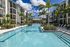 Luxurious apartment complex surrounding a sparkling resort-style pool with palm trees and lounge chairs, perfect for relaxation and leisure.
