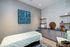 Tranquil wellness room with a cozy treatment bed, modern cabinetry, and elegant artwork creating a serene atmosphere.