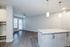 Bright and modern open-concept living space with sleek hardwood flooring, featuring a stylish kitchen island and elegant pendant lighting.