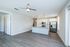 Modern living area with sleek hardwood floors, elegant ceiling fan, and bright kitchen featuring stainless steel appliances and stylish pendant lighting.