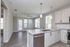 Modern open-concept apartment kitchen with sleek countertops, pendant lighting, and bright living area with large windows and elegant wood flooring.