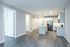 Modern open-concept kitchen with sleek cabinetry, island countertop, and stainless steel appliances in a bright, spacious apartment layout.