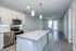 Stylish modern kitchen with sleek white cabinetry, stainless steel appliances, and a spacious granite island opening to a bright living area with large windows and elegant lighting.