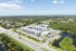 Aerial view of modern apartment complex surrounded by lush greenery and scenic water features, offering spacious living and convenience in a serene suburban setting.