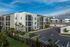 Contemporary apartment complex showcasing modern architecture with lush landscaping and ample parking.