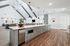Modern open-concept kitchen with sleek countertops, elegant cabinetry, and stylish pendant lighting, adjacent to a spacious living area with high ceilings and chic decor.