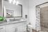 Elegant bathroom featuring sleek gray tiles, a modern white vanity with granite countertop, and a spacious walk-in shower, offering a luxurious touch to any home.
