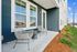 Charming apartment patio with elegant wicker chairs, stylish blue siding, and lush landscaping for a welcoming outdoor retreat.