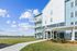 Contemporary apartment building with modern balconies, lush landscaped surroundings, and clear blue skies offering serene living.