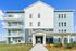 Modern apartment building with stylish balconies and fresh landscaping under a clear blue sky.