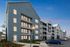 Modern apartment complex with spacious balconies and stylish blue facade, set against a serene evening sky.