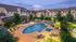 a swimming pool in the evening hours surrounded by a large deck and lounge chairs