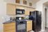 Stylish kitchen with natural wood cabinets, black appliances, and granite countertops.