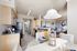 Bright apartment interior showcasing an open-concept kitchen with beige cabinetry, dining area, and stylish living room.