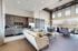 Spacious modern living area with large windows, comfortable seating, and elegant kitchen cabinets.