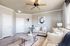 Elegant living room with light-colored sofas, modern artwork, and a sleek ceiling fan.