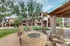 Charming apartment exterior with a cozy outdoor seating area around a stone fire pit, surrounded by lush greenery and mature trees.