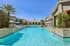 Luxurious resort-style swimming pool with crystal-clear water, surrounded by elegant loungers and lush greenery, offering a serene retreat.