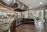 Luxurious modern clubhouse kitchen with sleek stainless steel appliances, stylish marble countertops, and a bright, open layout.