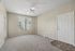Bright and airy living space with plush carpeting, a ceiling fan, and large window offering scenic views.