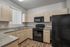 Modern kitchen with sleek black appliances, light wood cabinetry, featuring a spacious layout with ample natural light.