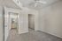 Bright, modern bedroom with plush carpeting, ceiling fan, and mirrored closet door.