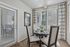 Bright dining area with elegant round table set, natural light streaming through large windows, and stylish decor creating a welcoming atmosphere.