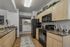 Modern kitchen with sleek black appliances, polished countertops, and elegant cabinetry, opening to a convenient laundry area.