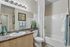 Modern bathroom featuring stylish vanity mirror with bright lighting and elegant artwork.