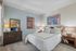 Inviting bedroom with modern art on pastel walls, plush carpeting, and elegant wooden furniture offering cozy comfort.