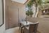 Cozy apartment patio with modern wicker chairs, small table, and lush green view, ideal for relaxing outdoors.