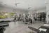 Modern fitness center with state-of-the-art equipment, including treadmills, weight machines, and exercise bikes, in a bright, spacious room with natural light and sleek wood flooring.