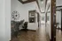 Modern open corridor with elegant workspace, featuring chic decor, large clock, and comfortable seating on sleek tiled flooring.