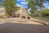 Charming outdoor patio with a stone fireplace surrounded by lush greenery and modern apartment buildings.