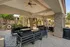 Inviting outdoor seating area with stylish black cushioned benches and ceiling fans under a rustic stone archway, perfect for relaxation and social gatherings.