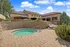Elegant outdoor setting featuring a luxurious spa with shaded seating, surrounded by lush greenery and modern architecture.