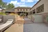 Elegant entrance to a stylish residential building with modern architecture, featuring sleek steps and comfortable outdoor lounge chairs.
