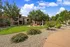 Charming apartment complex with lush green spaces, a shaded gazebo, and inviting seating area for relaxation under a bright blue sky.