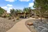 Charming apartment complex courtyard with a stylish pergola, grilling stations, and lush landscaping under a bright blue sky.