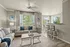Bright and airy modern living room with plush beige sofas, elegant d&eacute;cor, and large sunlit windows offering a view of lush greenery.
