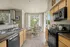 Charming kitchen with modern appliances, sleek countertops, and a sunlit dining area surrounded by elegant curtains.