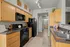 Sleek modern kitchen with stylish wood cabinetry, black appliances, and elegant countertops, leading to a bright dining area.
