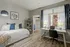 Cozy bedroom with modern design, featuring a daybed with plush pillows, stylish workspace with ample natural light, and a walk-in closet for added convenience.