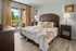 Inviting bedroom with elegant wooden furniture, floral bedding, and natural light streaming through large sliding doors opening to a cozy balcony.